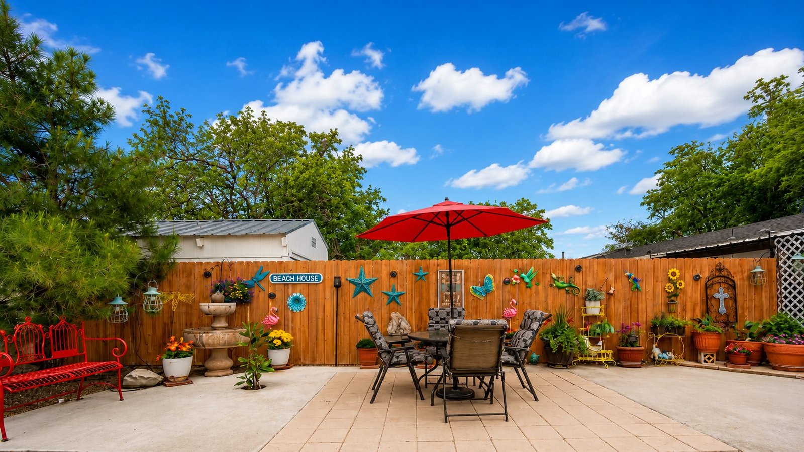 Open-air sitting area with tables, flowers, and a red umbrella at Capri Motel