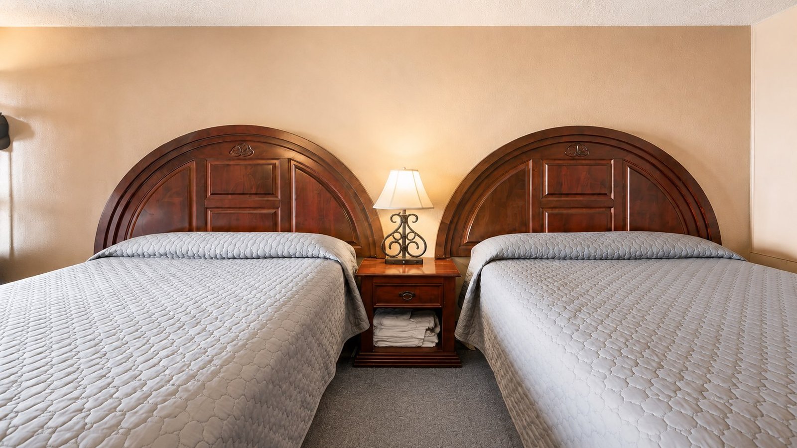 Two neatly made beds inside a Capri Motel room