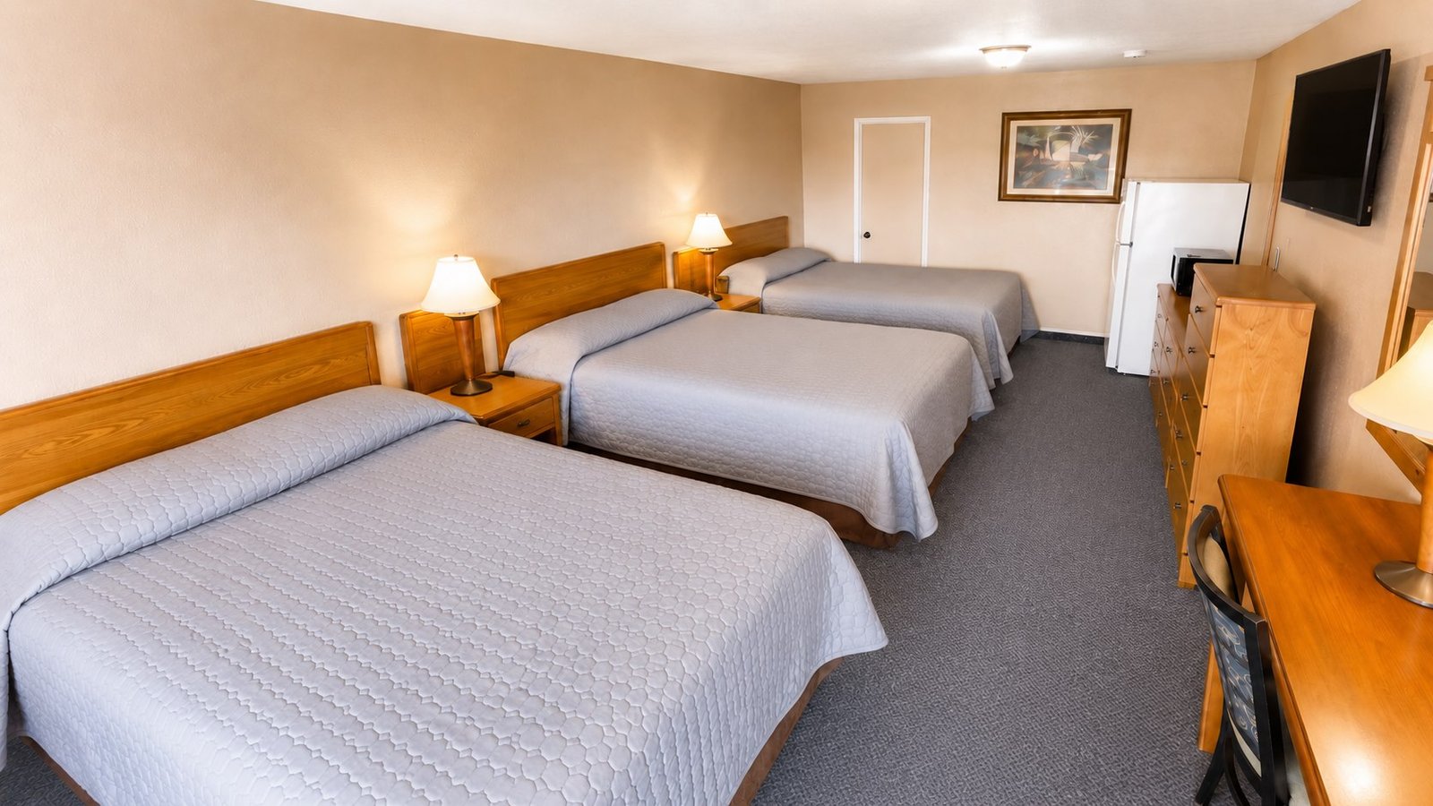 A spacious Capri Motel room with three neatly made beds